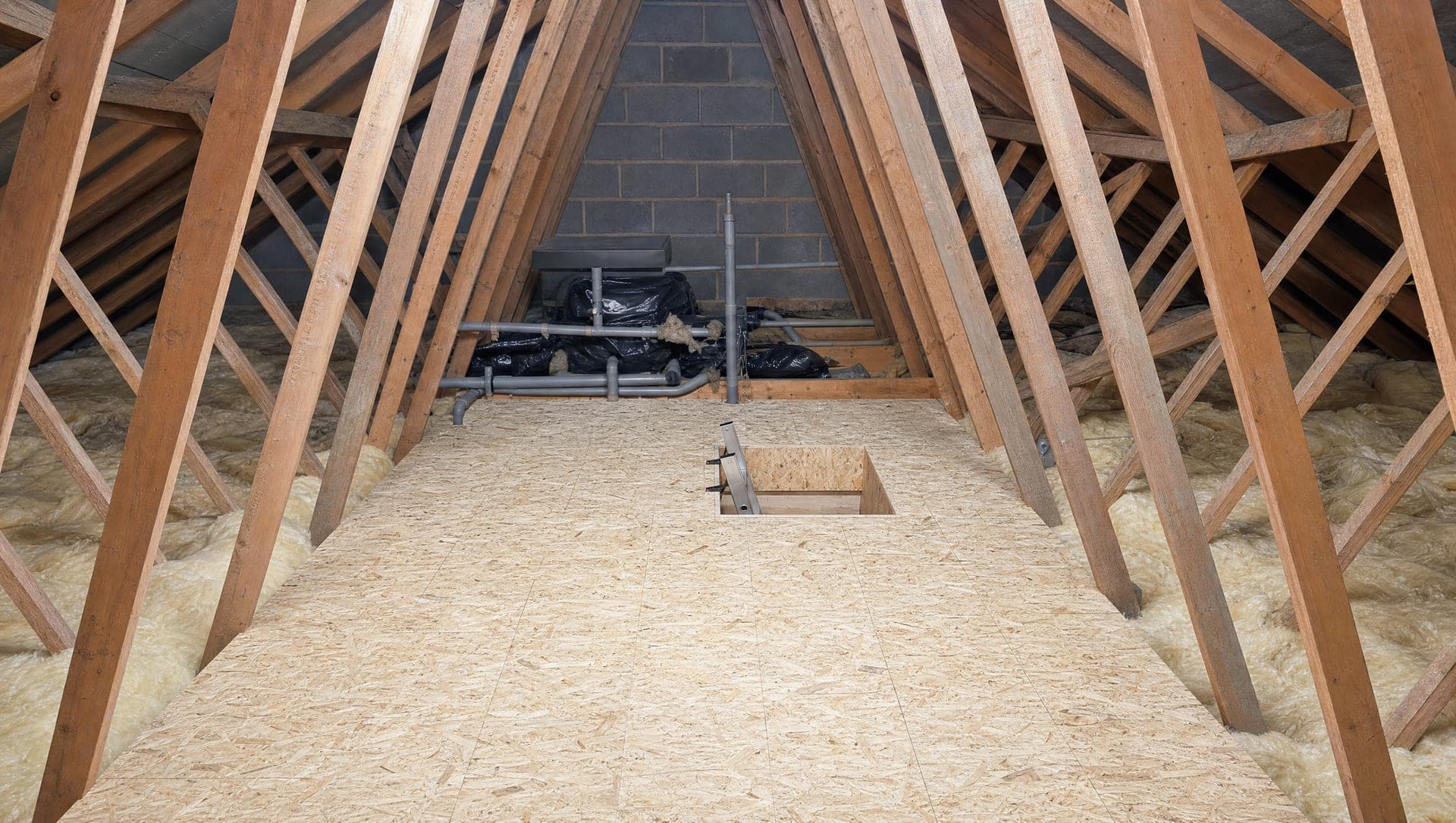 A residential home under construction with timber framing, sheathing and uninstalled windows visible at the front porch