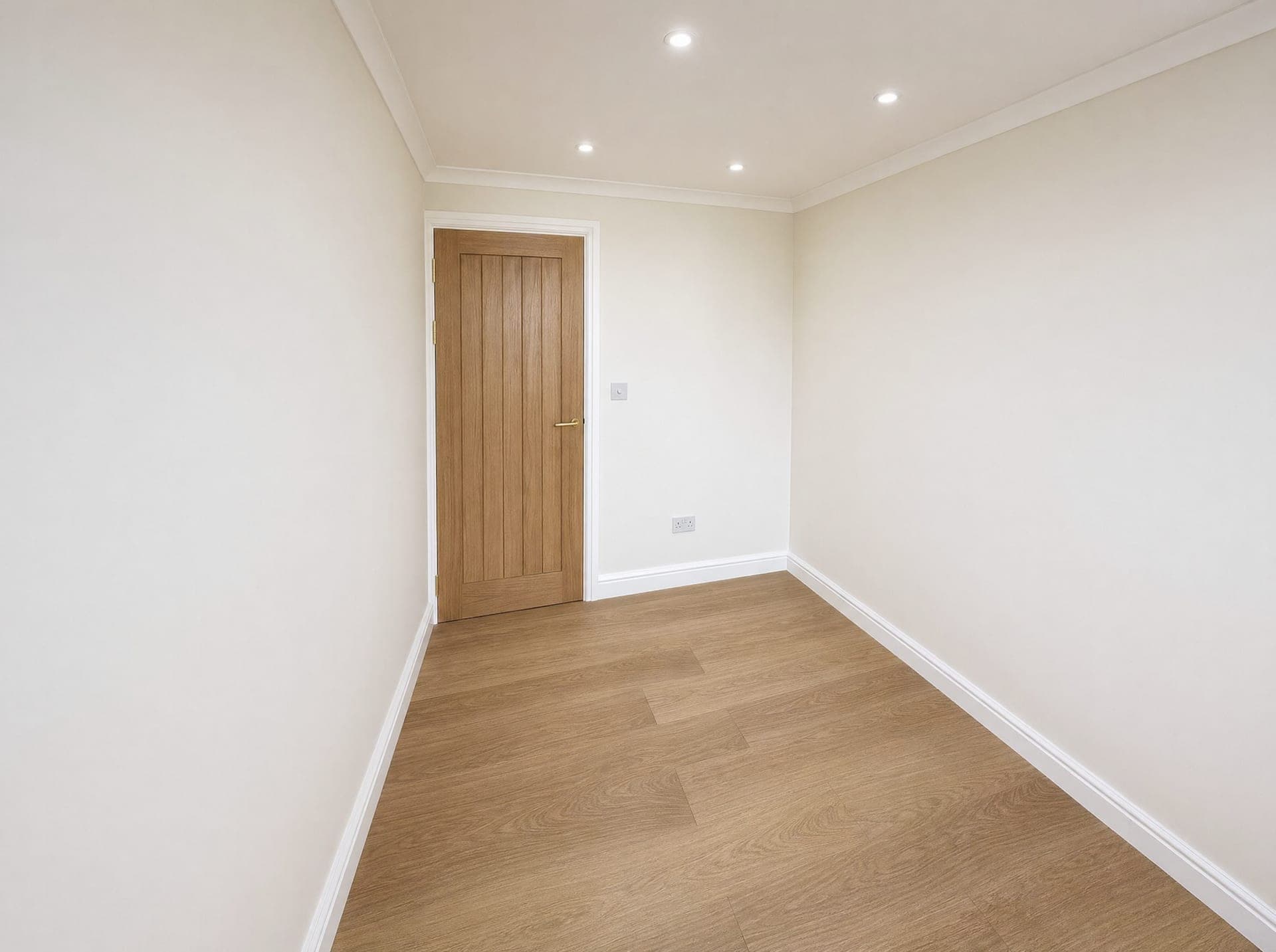 Empty bedroom with oak panelled door, recessed downlights and wood-effect flooring