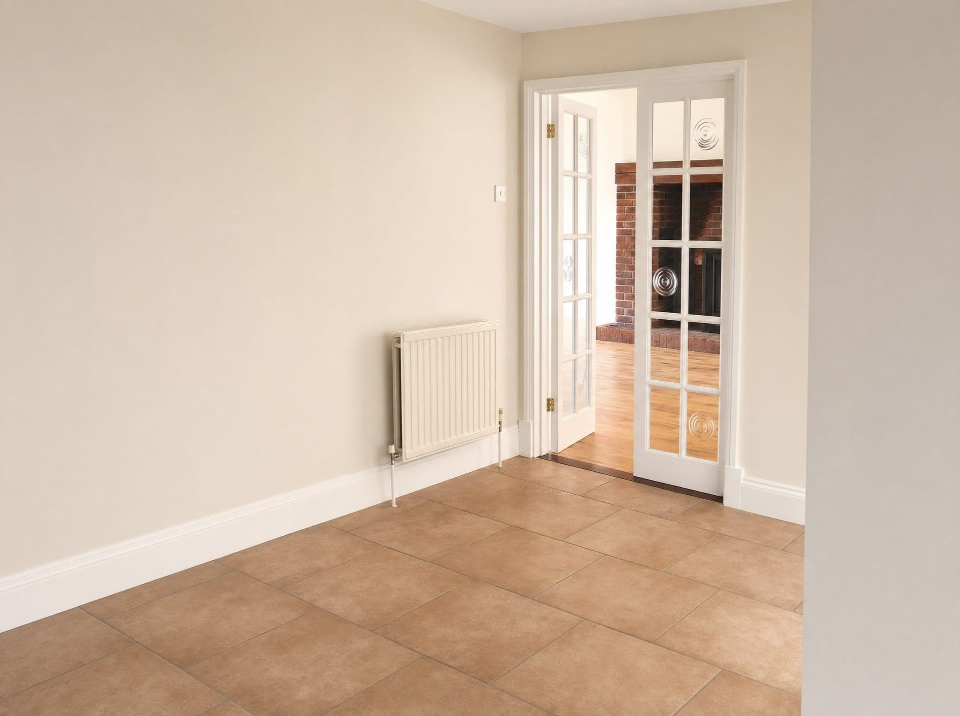 Empty room with terracotta tiles and glazed double doors with circular leaded detail