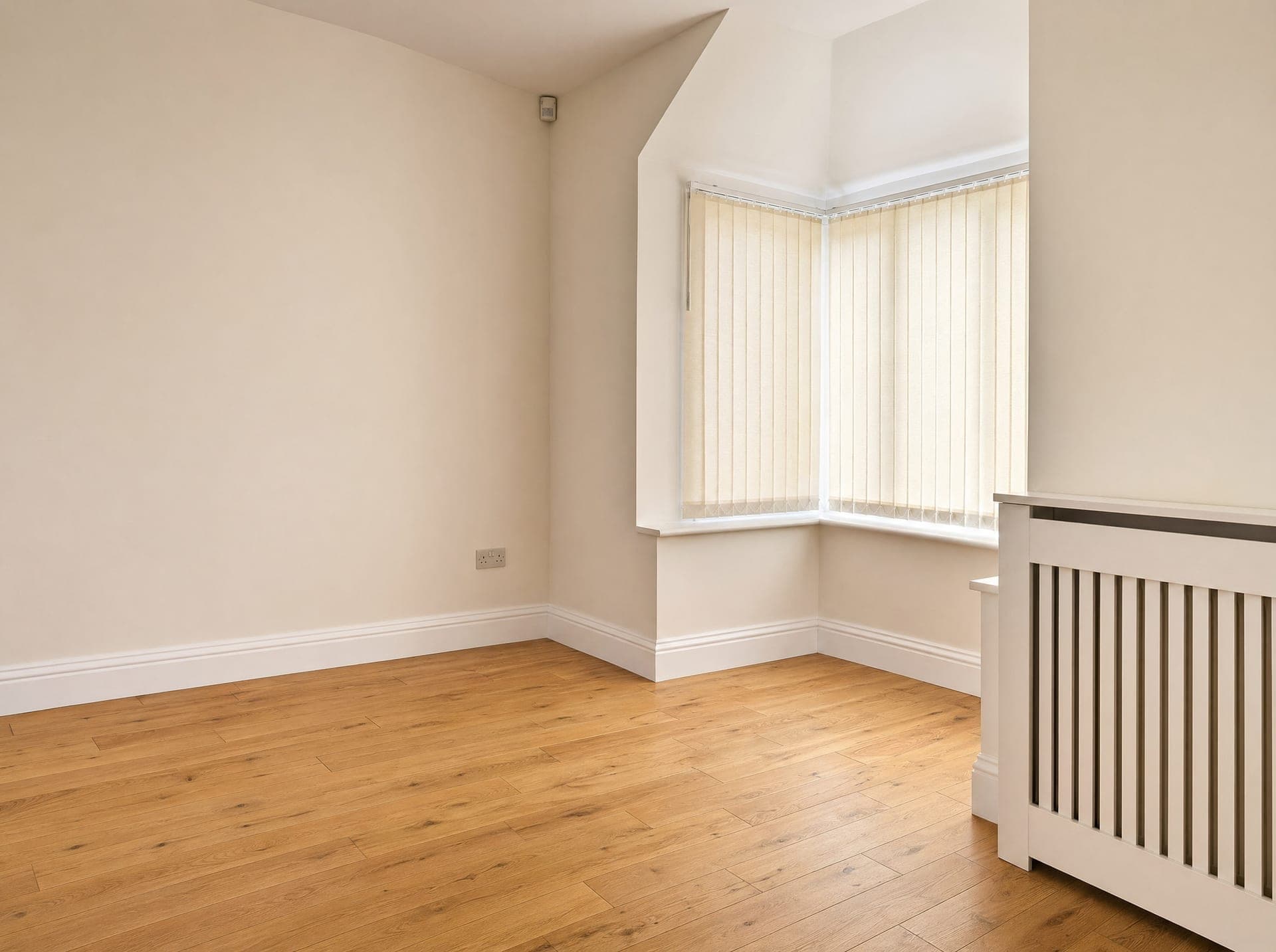 Reception room with bay window, cream vertical blinds, oak engineered flooring and a white radiator cover