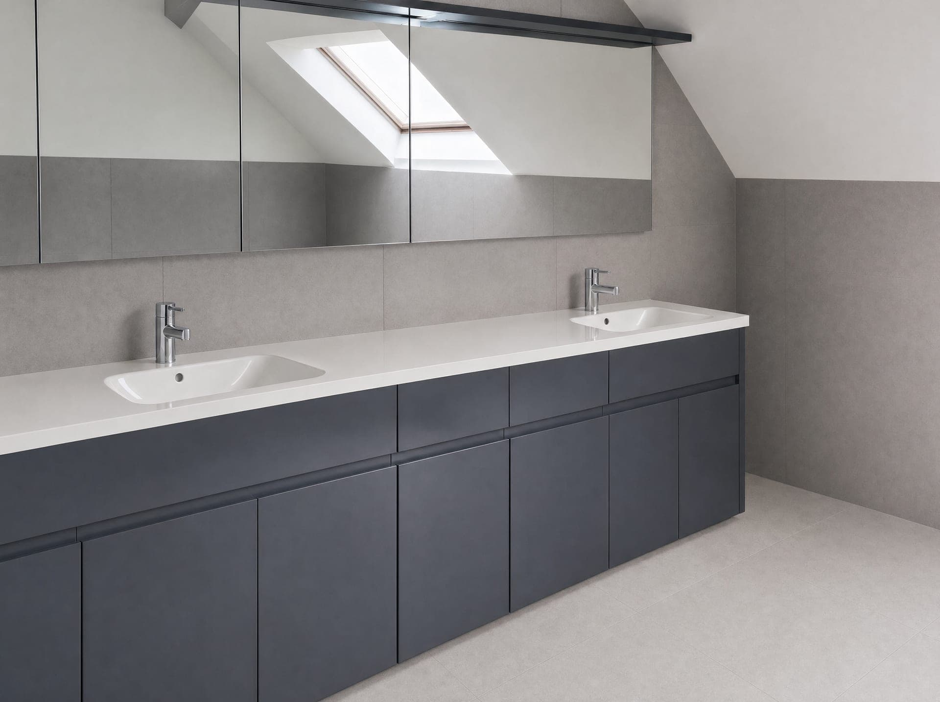 Loft bathroom with double basin vanity, dark grey handleless units and Velux window above