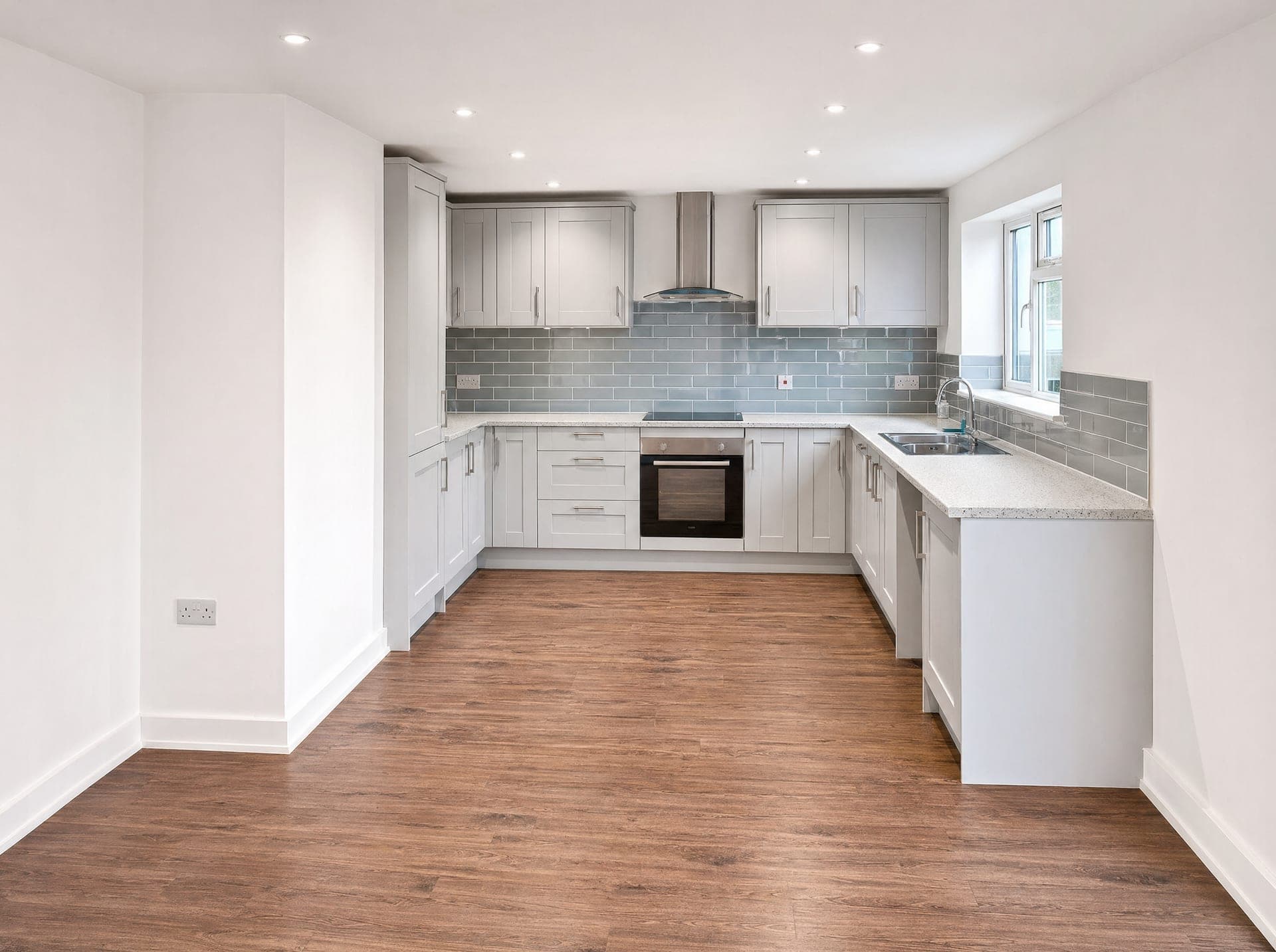 U-shape kitchen with grey shaker units, stone-effect worktop, integrated oven and a metro tile splashback
