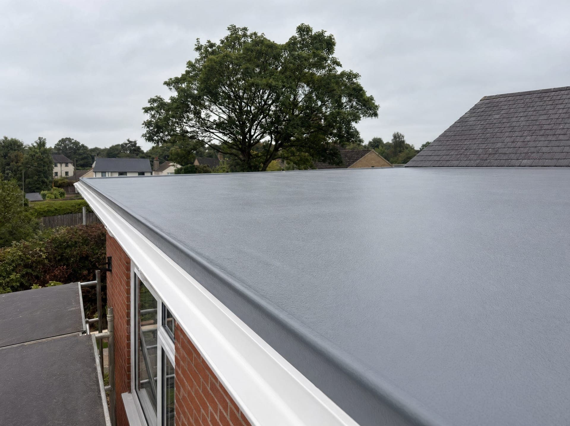 GRP fibreglass flat roof detail showing the white kerb edge trim, white guttering and brickwork
